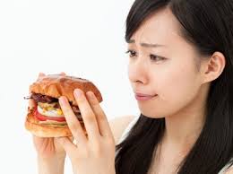 ハンバーガーを食べるのを躊躇う女性